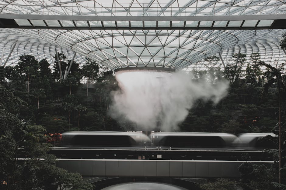 Modern indoor scene with a waterfall and blurred trains at Jewel Changi Airport, Singapore.